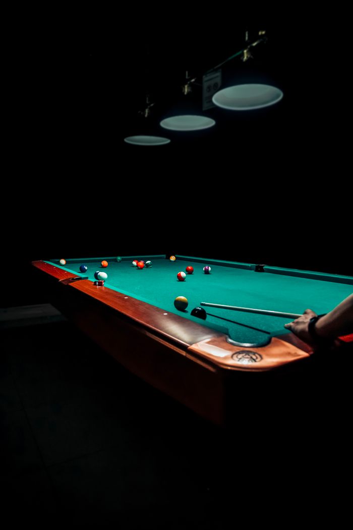 A dramatic and focused image of a billiards game under dim lighting, highlighting the intensity of the sport.