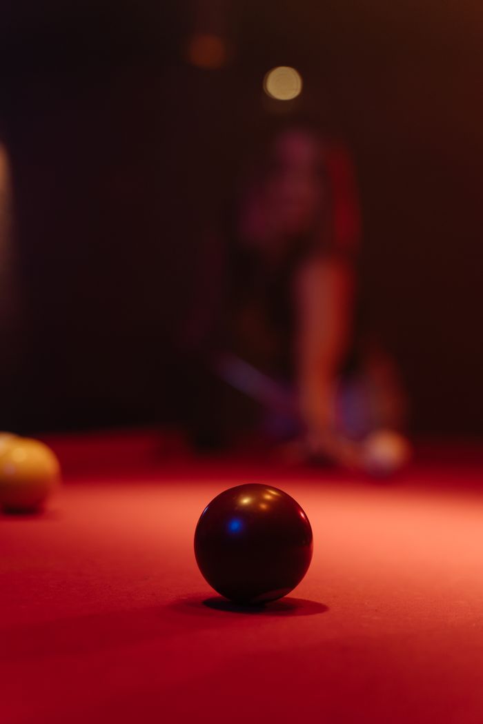 A close-up of a billiard ball on a red pool table with dramatic lighting and shallow depth of field.